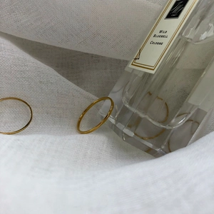 Close-up of two minimalist gold stacking rings on textured white fabric with soft lighting