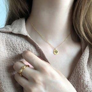 Elegant gold wavy ring and evil eye pendant necklace worn by a fashion model