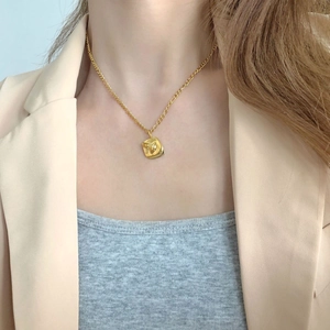Gold abstract face pendant necklace on model wearing beige blazer minimalist luxury style