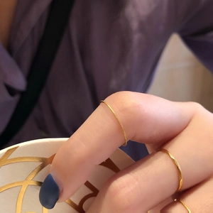 Détail de bagues minimalistes dorées fines avec finitions mate et polie portées au doigt