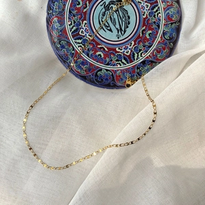 Elegant gold minimalist necklace with delicate flat heart-shaped links on white linen background