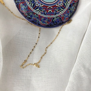 Minimalist 18K gold chain necklace featuring geometric links on white linen background