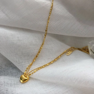 Elegant gold double layer necklace with 18K heart pendant on white fabric background