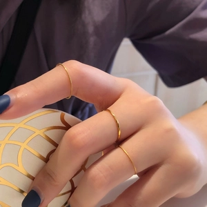 Gros plan de fines bagues empilables en or 18 carats avec une texture mate sur les doigts