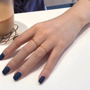 Ensemble de trois bagues empilables fines plaquées or 18 carats sur une main de femme