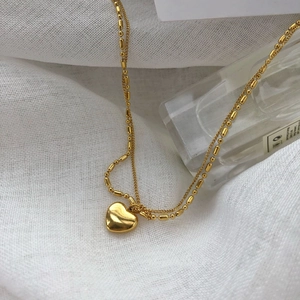 Vintage double layer gold heart pendant necklace with layered chain design on white linen