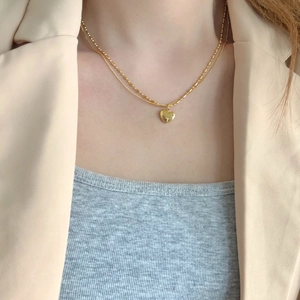 Close-up of double-layer gold chain necklace with heart pendant on model