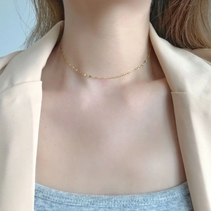 Minimalist geometric gold layered necklace shown on a model with elegant beige suit