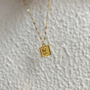 Collier en acier titane doré avec pendentif carré et relief de rose détaillé