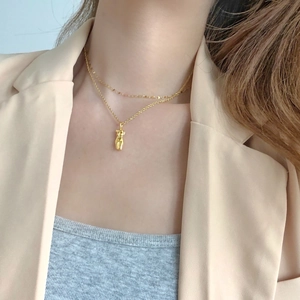 Close-up of golden double-layer necklace with 3D female body silhouette pendant on model