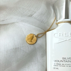 Detailed shot of golden prayer hands pendant on ball chain with inspiring engraving