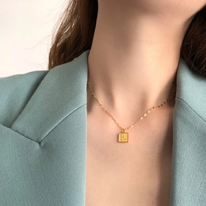 Détail du pendentif rose carré doré avec une chaîne à paillettes sur le cou