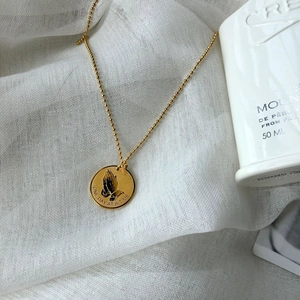 Hip-hop gold prayer hands pendant necklace with bead chain on white textile surface