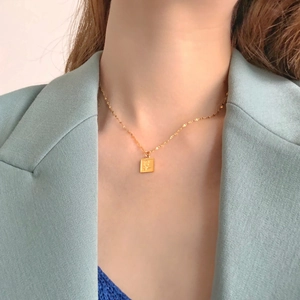 Gros plan d'un collier en acier titane avec pendentif carré et motif de rose en relief