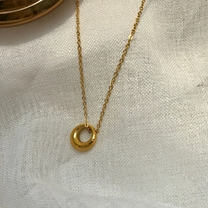 Minimalist gold hollow circle pendant necklace with a polished mirror finish on linen