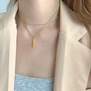 Artistic gold layered necklace featuring an abstract female torso pendant on a female model