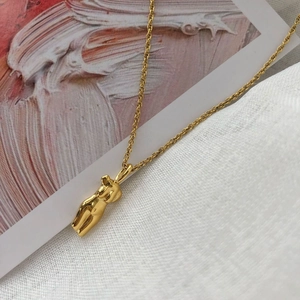 Collier doré artistique avec pendentif silhouette féminine sur fond minimaliste