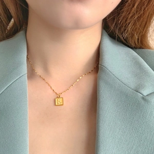 Vue détaillée d'un collier pendentif rose carrée dorée avec chaîne torsadée sur modèle