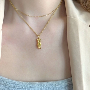 Double-layered gold necklace with abstract female torso pendant on an elegant model