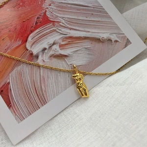 Pendentif sculpture dorée sur collier délicat avec arrière-plan peinture abstraite