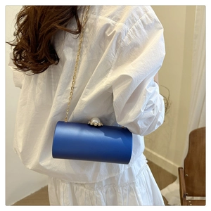 Sac de soirée cylindrique en satin bleu roi avec fermoir perle et chaîne dorée sur modèle