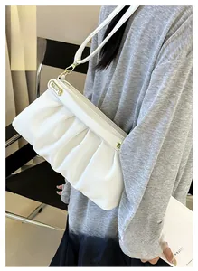Close-up of pleated white leather texture and golden metal hooks on a stylish handbag