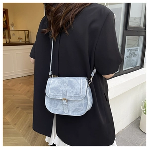 Light blue vintage saddle bag with metal buckle shown in a stylish street style setting