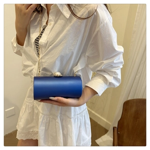 Détail du sac de soirée cylindre en satin bleu roi avec fermoir perle et chaîne dorée