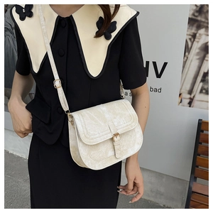 Close-up of beige vintage saddle bag with textured leather and gold buckle detail
