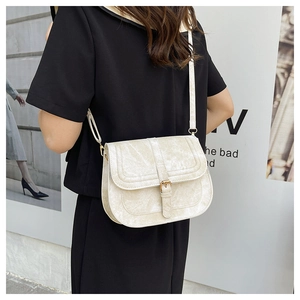 Detail of cream saddle bag featuring marble texture and gold hardware on black outfit