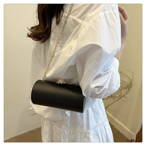 Détail de la pochette cylindrique avec fermoir perle géante et bandoulière dorée
