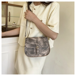 Detail of vintage textured crossbody bag with metal buckle and weathered canvas finish