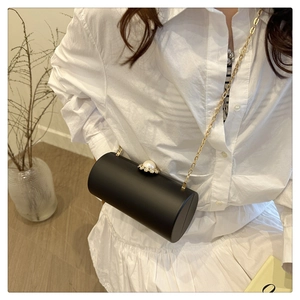 Détail du sac de soirée cylindrique noir avec perles et strass sur le dessus et chaîne