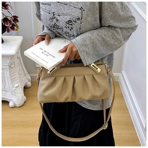 Detailed close-up of khaki ruched leather handbag with adjustable strap and gold hardware
