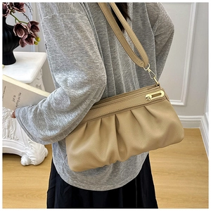 Detailed macro view of beige pleated leather bag with gold buckle and lychee texture
