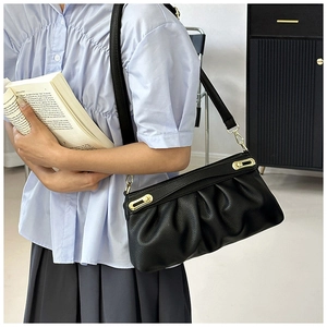 Detail of black pleated faux leather shoulder bag with gold buckles and lychee texture