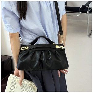 Detail of soft black pleated leather handbag featuring elegant golden metal hardware accents