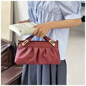 Close-up of wine red lychee leather texture and golden metal buckle on pleated handbag