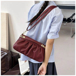 Close-up of wine red pleated leather texture with gold metal buckle on a shoulder bag