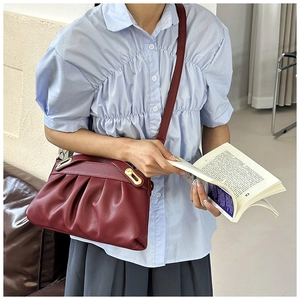 Detail of burgundy soft leather tote with pleated design and gold oval metal buckle