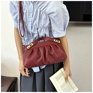 Detail of burgundy ruched faux leather handbag with gold metal buckle and shoulder strap