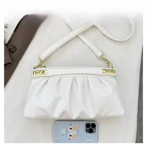 Detail view of white pebbled leather bag with gold hardware and size comparison to a phone