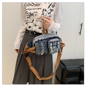 Detail der Vintage-Umhängetasche aus gewaschenem Denim mit braunem Webriemen und Taschen
