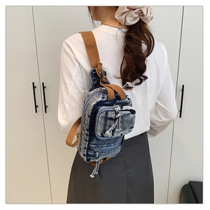 Detailansicht der gewaschenen Denim-Brusttasche mit braunem Webriemen an einem Model