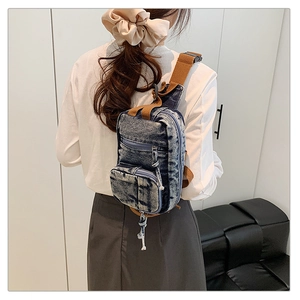 Detail der Vintage-Brusttasche aus Denim mit verstellbarem braunem Gurt und Schnallenverschluss