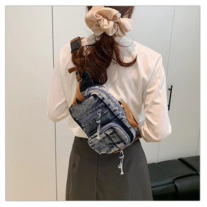 Detail der gewaschenen Denim-Umhängetasche mit mehrlagigen Reißverschlüssen und Nylonriemen