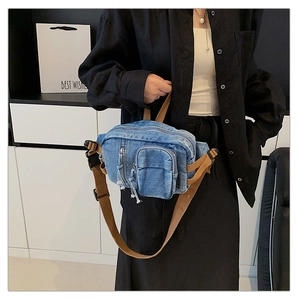 Nahaufnahme der blauen gewaschenen Denim-Brusttasche mit braunen Nylonbändern und Reißverschluss