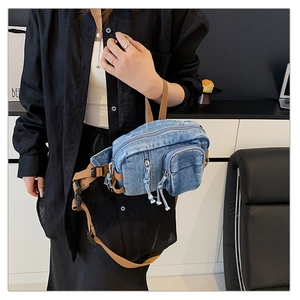 Detail der hellblauen Brusttasche aus gewaschenem Denim mit braunem Segeltuchgurt