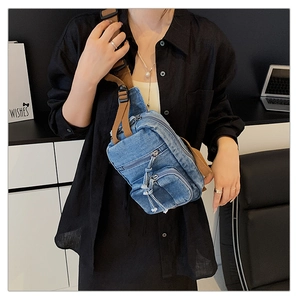 Detail der blauen Denim-Umhängetasche mit braunem Gurt und mehreren Reißverschlussfächern