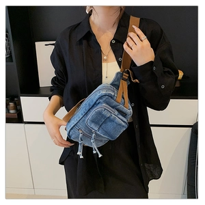 Detail der blauen Denim-Umhängetasche mit braunem Gurt und Reißverschlüssen am Modell